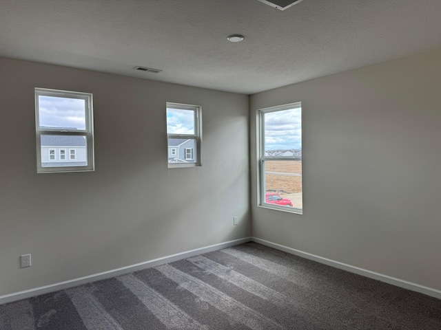 carpeted empty room with visible vents, baseboards, and a textured ceiling