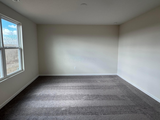 empty room with dark carpet and baseboards