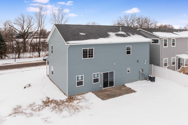 snow covered back of property featuring central AC