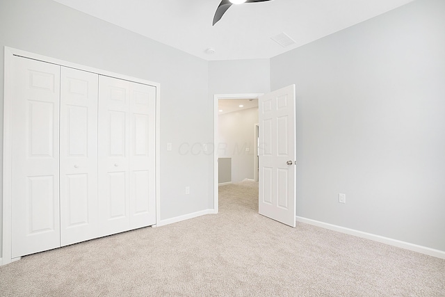 unfurnished bedroom featuring ceiling fan, light carpet, and a closet