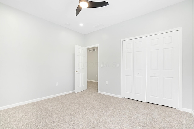 unfurnished bedroom with ceiling fan, light colored carpet, and a closet