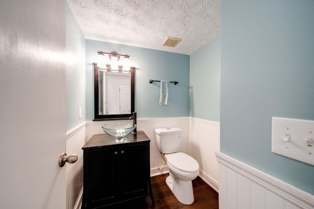 bathroom with toilet, vanity, a textured ceiling, and hardwood / wood-style floors