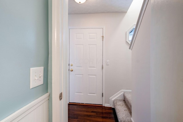 doorway featuring a textured ceiling and dark hardwood / wood-style floors