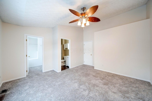 unfurnished bedroom featuring a textured ceiling, light carpet, connected bathroom, and ceiling fan