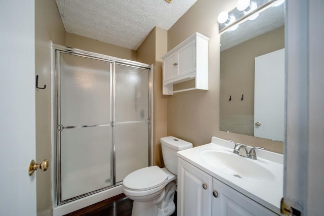 bathroom with toilet, a textured ceiling, a shower with door, and vanity