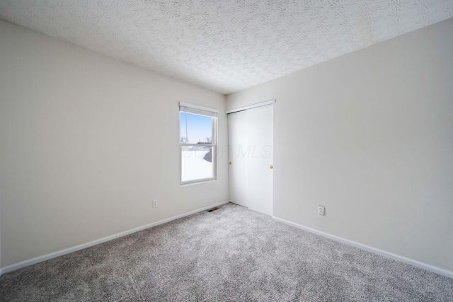 unfurnished room featuring a textured ceiling and carpet