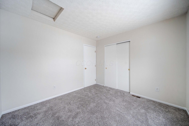 unfurnished bedroom featuring a textured ceiling, a closet, and carpet flooring