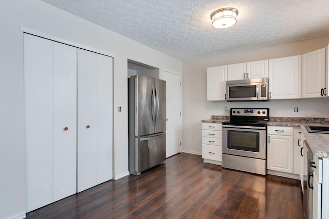 kitchen with white cabinets, stainless steel appliances, dark hardwood / wood-style flooring, and a textured ceiling