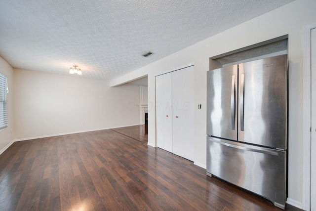 kitchen with a textured ceiling, stainless steel fridge, and dark hardwood / wood-style floors