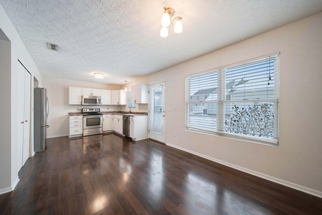 kitchen featuring white cabinets, a textured ceiling, appliances with stainless steel finishes, and dark hardwood / wood-style flooring