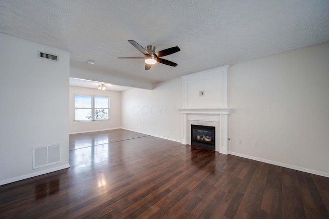 unfurnished living room with dark hardwood / wood-style flooring, a textured ceiling, and a large fireplace