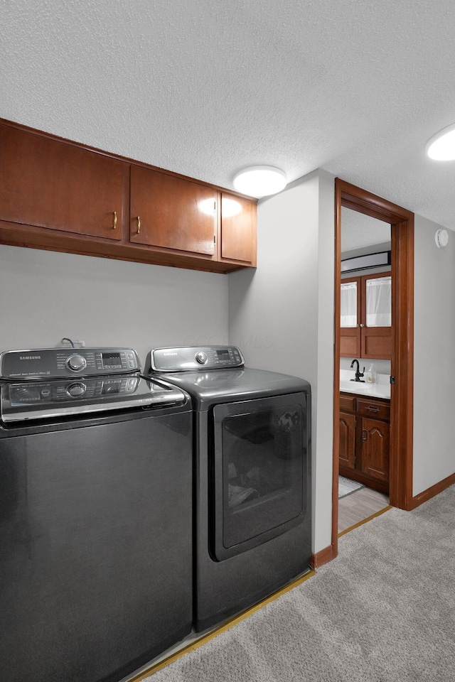 washroom with sink, cabinets, light colored carpet, a textured ceiling, and washer and dryer