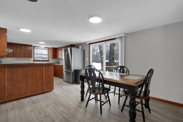 dining space featuring light hardwood / wood-style floors and a textured ceiling