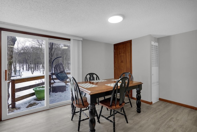 dining area with a textured ceiling and light hardwood / wood-style flooring