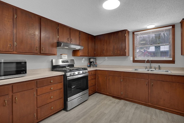 kitchen with sink, light wood-type flooring, a textured ceiling, and appliances with stainless steel finishes