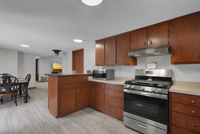 kitchen with kitchen peninsula, light hardwood / wood-style floors, a textured ceiling, and appliances with stainless steel finishes