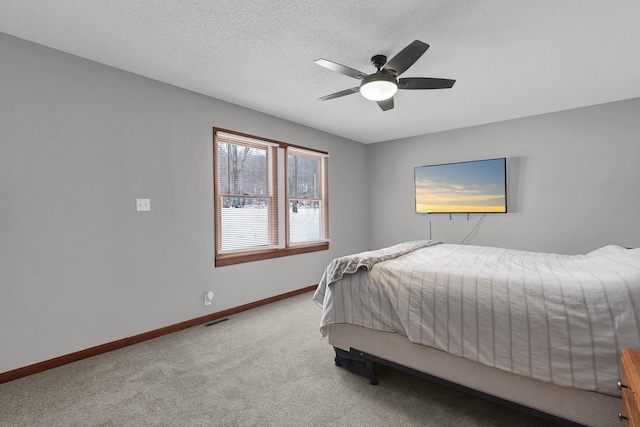 bedroom with ceiling fan, light colored carpet, and a textured ceiling