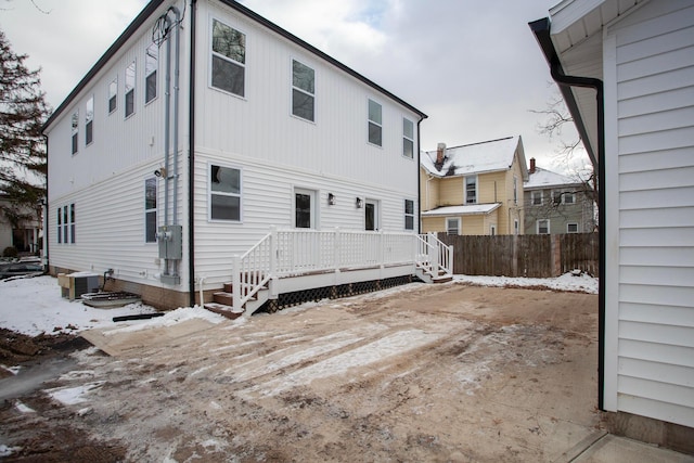 snow covered property featuring cooling unit and a deck