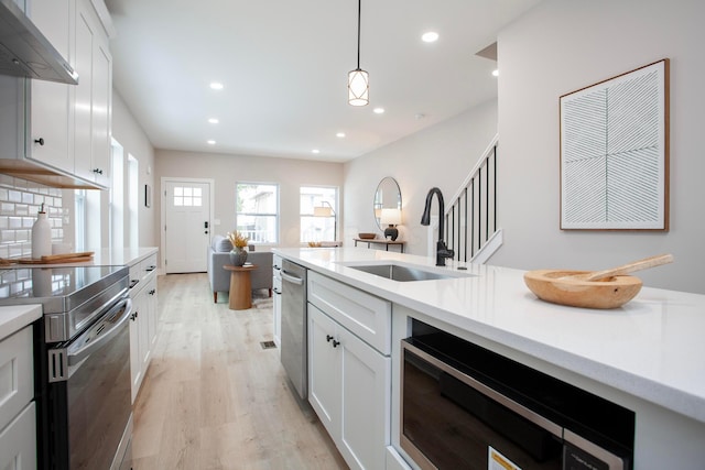 kitchen featuring pendant lighting, white cabinetry, extractor fan, and sink