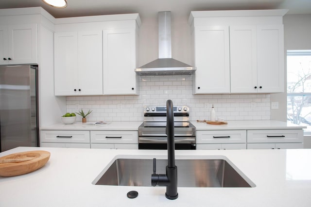 kitchen with tasteful backsplash, white cabinetry, wall chimney exhaust hood, and stainless steel appliances