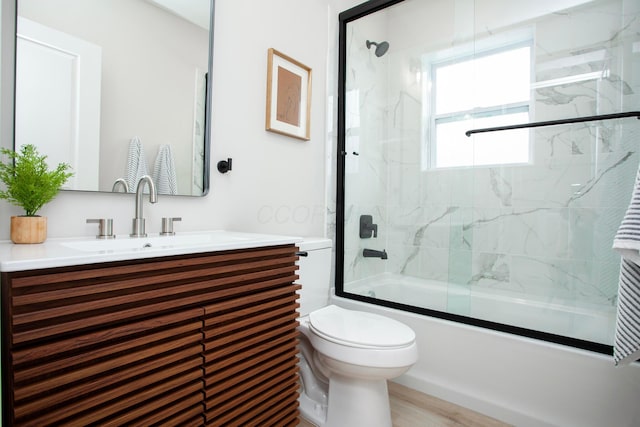 full bathroom featuring vanity, toilet, wood-type flooring, and bath / shower combo with glass door