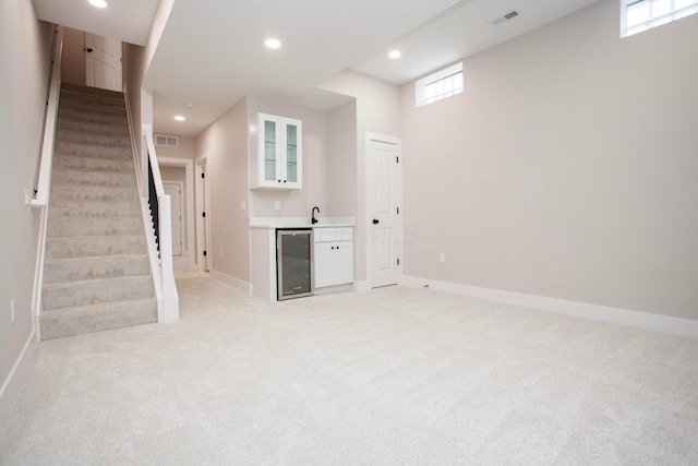 basement featuring wine cooler, sink, and light colored carpet