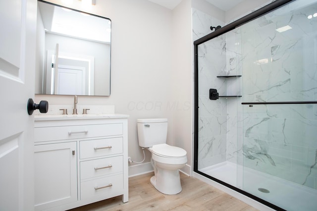 bathroom with hardwood / wood-style floors, vanity, a shower with door, and toilet