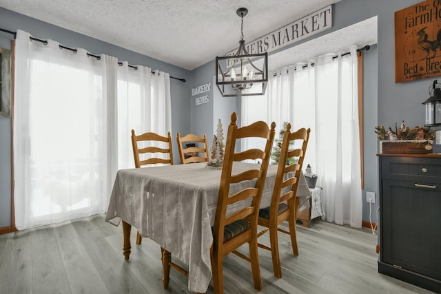 dining room featuring light hardwood / wood-style floors, a textured ceiling, and a chandelier