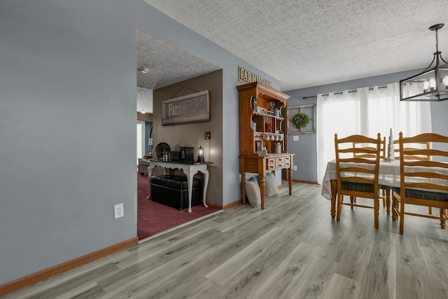 dining room with a notable chandelier, a textured ceiling, and light wood-type flooring