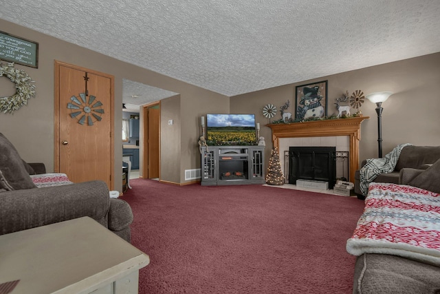 living room with a textured ceiling, carpet floors, and a tiled fireplace