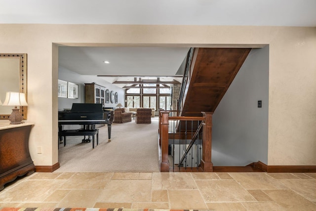 interior space with baseboards, carpet flooring, stone tile flooring, and an upstairs landing