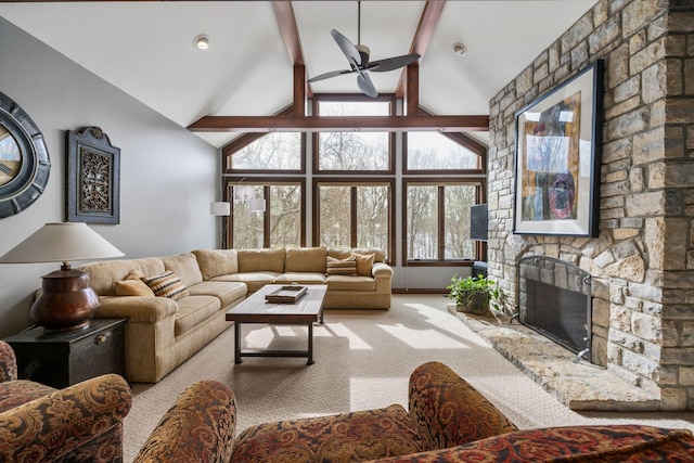 carpeted living room featuring high vaulted ceiling, a stone fireplace, a ceiling fan, baseboards, and beam ceiling