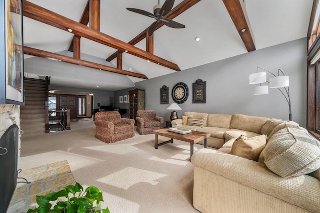 carpeted living room featuring ceiling fan, high vaulted ceiling, beam ceiling, and a stone fireplace