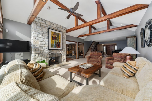 carpeted living room with high vaulted ceiling, a stone fireplace, a ceiling fan, stairs, and beam ceiling