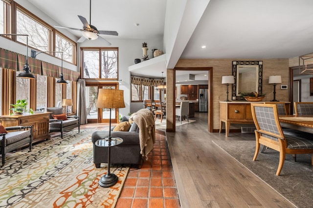 interior space with ceiling fan, a high ceiling, visible vents, and wood finished floors