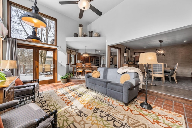 living area featuring ceiling fan with notable chandelier, high vaulted ceiling, and tile patterned floors