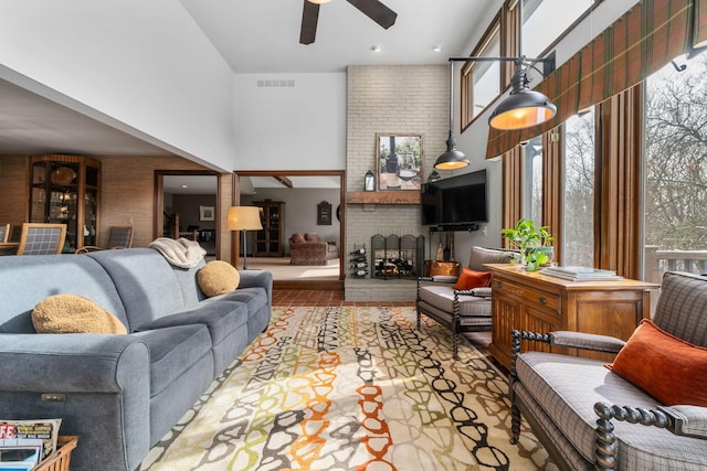 living room featuring visible vents, a high ceiling, a brick fireplace, and a wealth of natural light