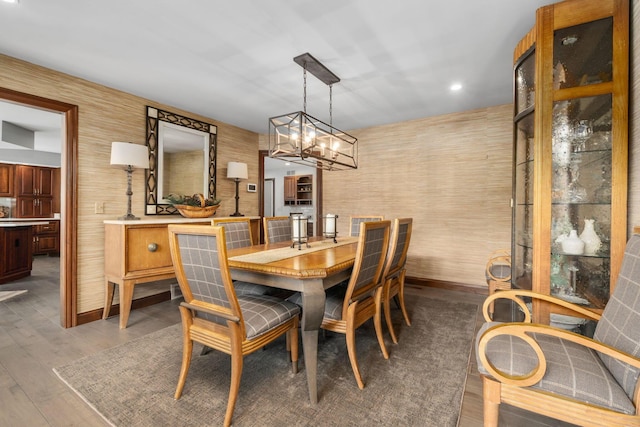 dining area with dark wood-style floors, a notable chandelier, and baseboards