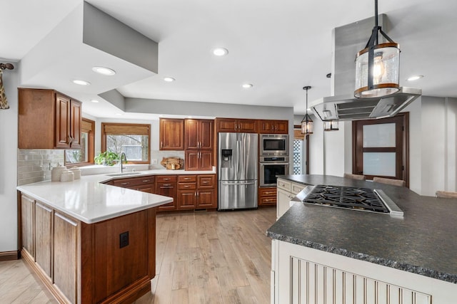 kitchen featuring island exhaust hood, tasteful backsplash, appliances with stainless steel finishes, a sink, and light wood-type flooring