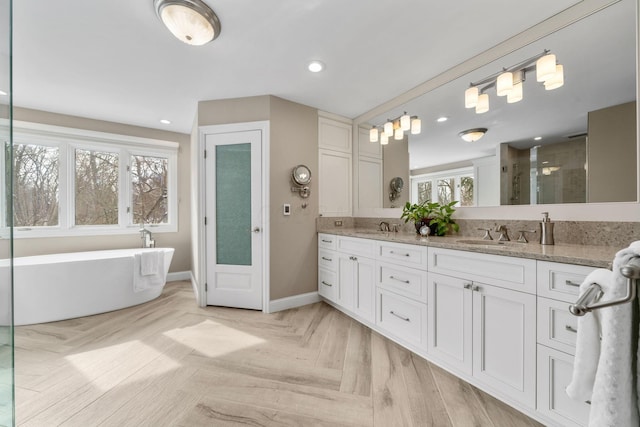 bathroom featuring double vanity, a stall shower, a freestanding bath, and a sink