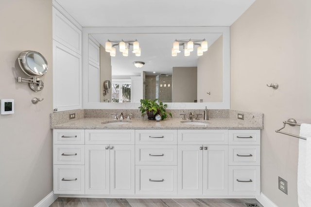 full bathroom featuring double vanity, a shower stall, baseboards, and a sink