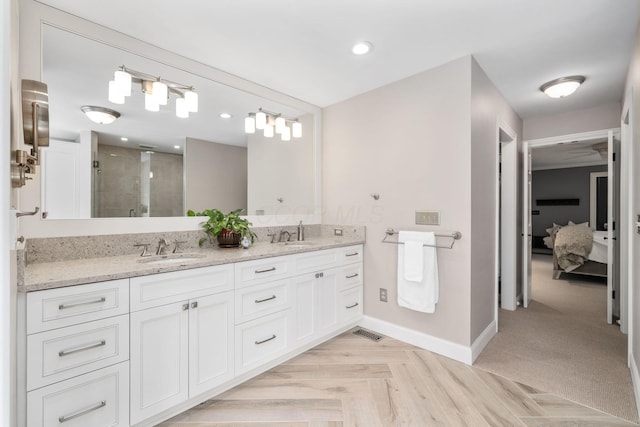 full bath featuring double vanity, a stall shower, a sink, and baseboards