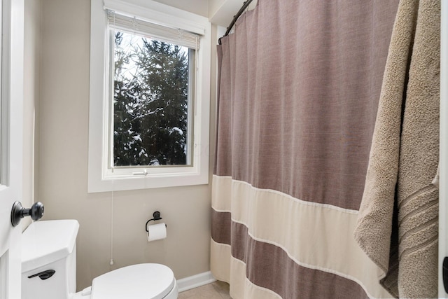 full bath with curtained shower, tile patterned floors, toilet, and baseboards