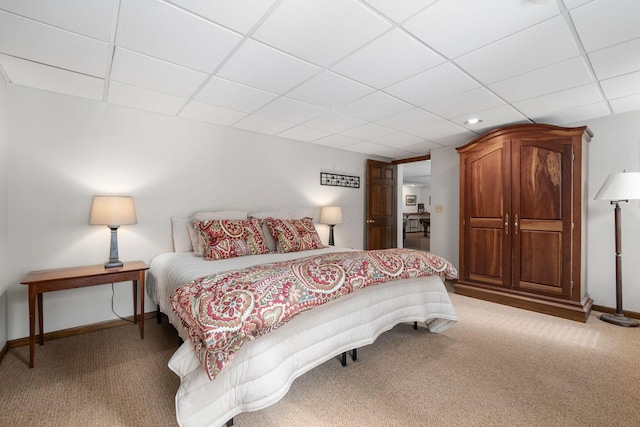 bedroom featuring light carpet, a paneled ceiling, and baseboards