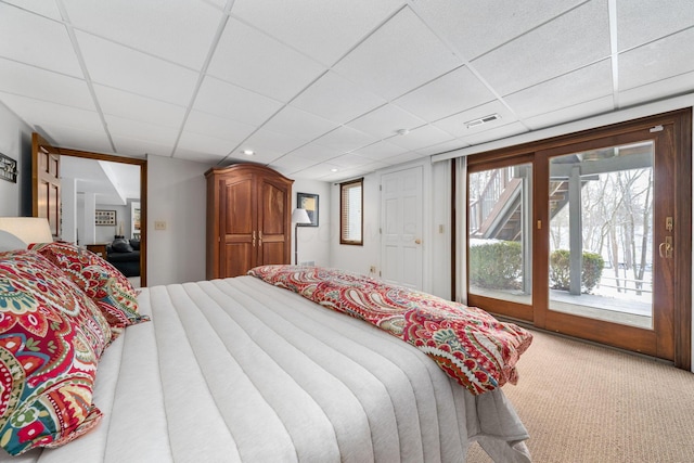 carpeted bedroom featuring access to outside, visible vents, and a paneled ceiling