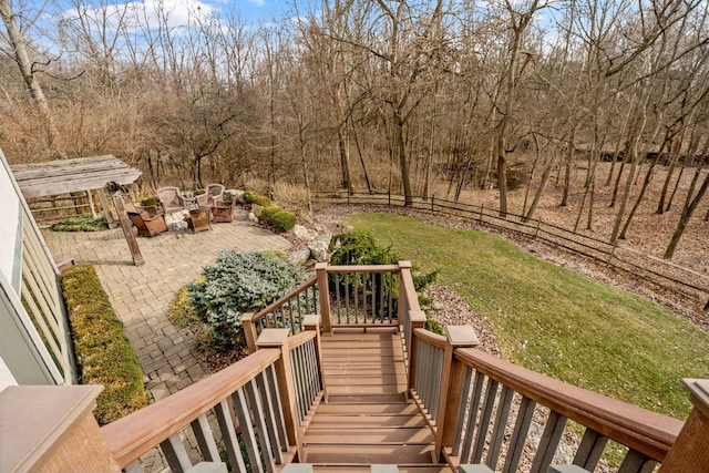 wooden terrace featuring a fire pit, fence, stairs, a lawn, and a patio area