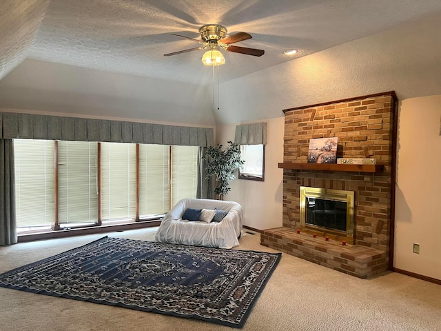 carpeted living room featuring ceiling fan, lofted ceiling, a fireplace, and a wealth of natural light