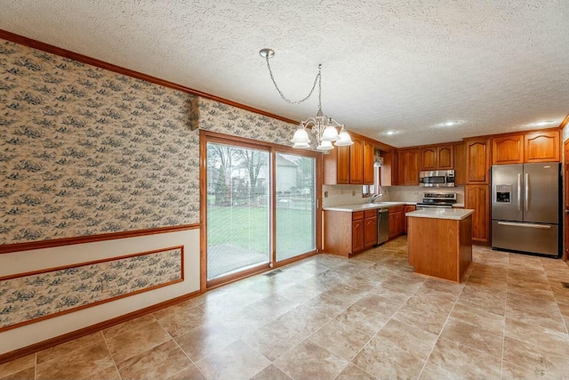 kitchen with stainless steel appliances, crown molding, an inviting chandelier, a kitchen island, and hanging light fixtures