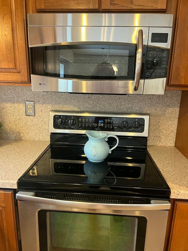 kitchen with decorative backsplash, light stone counters, and appliances with stainless steel finishes