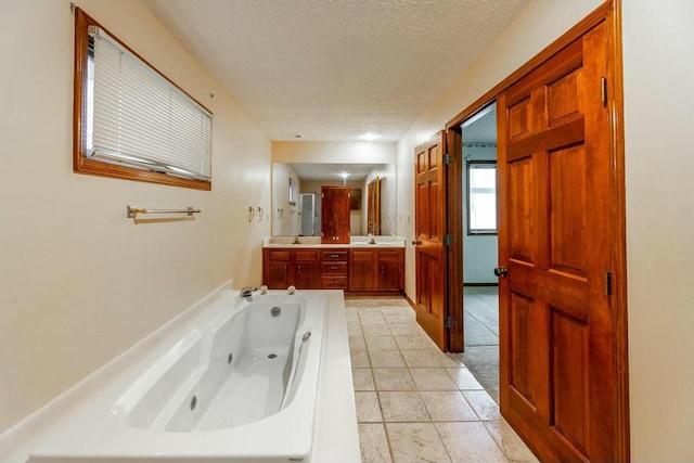 bathroom with tile patterned floors, vanity, a bath, and a textured ceiling